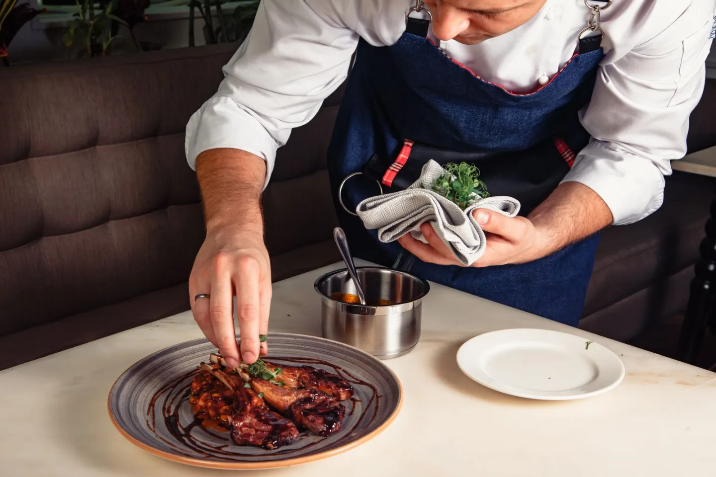 Profesional con chaquetilla blanca dando el acabado a un plato de restaurante