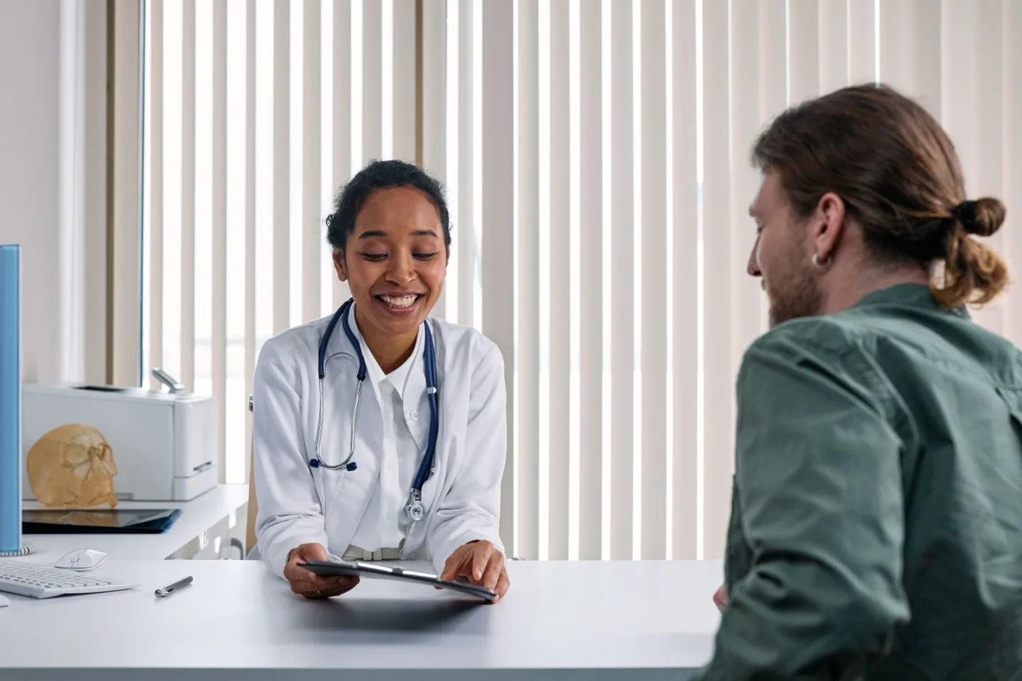 Profesional sanitario escuchando a un paciente durante una consulta